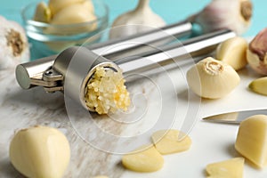 Garlic press and fresh cloves on board, closeup. Organic product