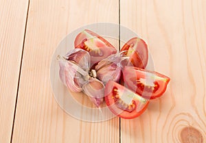 Garlic and sliced tomatoes on wood table.