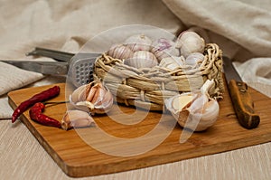 Garlic solo in a wicker basket on a wooden Board on a linen background. next to the knife, press