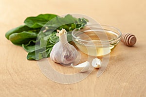 Garlic, spinach leaves and honey on a wooden background