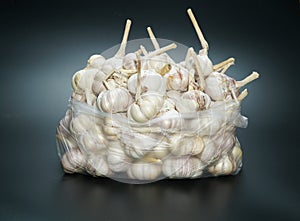 Garlic in a transparent bag on a black background.