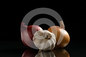 Garlic and two onions on a black background