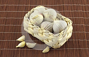 Garlic in wicker basket on straw mat