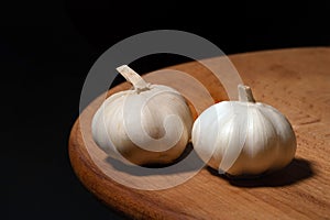 Garlic on a wooden kitchen board on a black background. Organic garlic