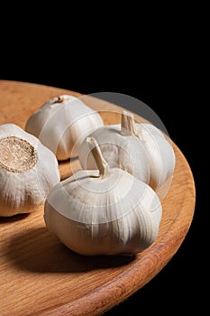 Garlic on a wooden kitchen board on a black background. Organic garlic