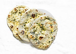 Garlicky herbs butter flatbread naan on a light background, top view