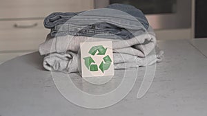 Garment recycling concept. There is a stack of clothes on the recycling table. Collection of clothes for recycling. Female hands f