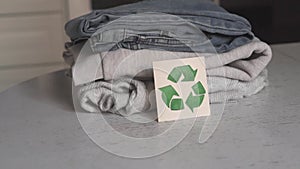 Garment recycling concept. There is a stack of clothes on the recycling table. Collection of clothes for recycling. Female hands f