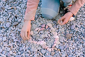 Garmony meditation, girl hand picking up heart from stones, relaxed hobby rest near sea