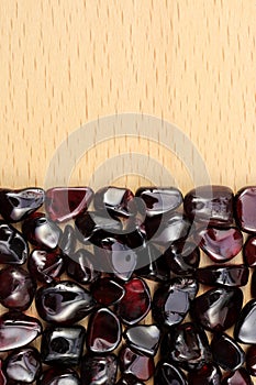 Garnet heap stones texture on half light varnished wood background. Place for text