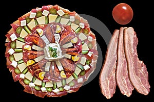Garnished Appetizer Savory Dish with Three Pork Belly Bacon Rashers and Cherry Tomato Isolated on Black Background