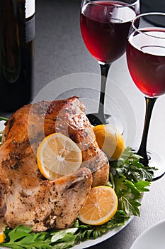Garnished roasted turkey on holiday decorated table with glasses of red wine