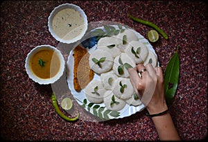Garnishing idli and sambhar dish with curry leaves