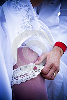 Garter bride leg and bridegroom hand with gold ring