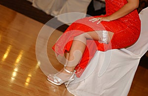 Garter on the bride`s leg red dress