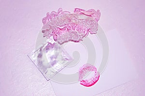 Garters, kiss and condom on white background