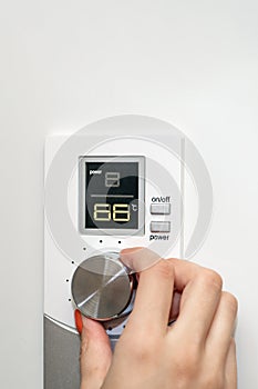 Gas boiler. A woman regulates the temperature with a temperature controller. Setting the room temperature by adjusting