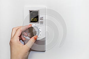 Gas boiler. A woman regulates the temperature with a temperature controller. Setting the room temperature by adjusting