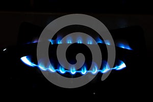 Gas burner with blue flame, glowing fire ring on kitchen stove