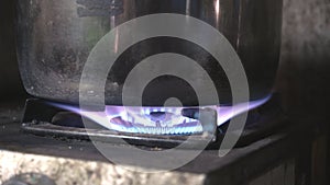 Gas burner with flame and stainless pot in the kitchen at home, cooking food.