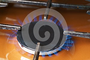 A gas burner on the kitchen stove with a blue flame. The concept of the gas market