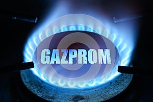 Gas burns in dark at home, blue fire flame and name Gazprom on stove ring burner photo
