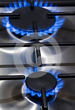 Gas Concepts. Closeup Macro Shoot of Two Gas Burners on Stove Surface with Fire Flames