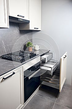 Gas cooker black glass and iron hob and hood on marble light stoneware countertop with horizontal sliding pull out