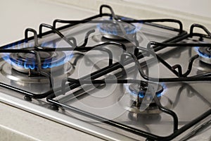 Gas cooktop with burning blue flames, closeup