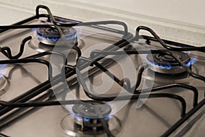 Gas cooktop with burning blue flames, closeup