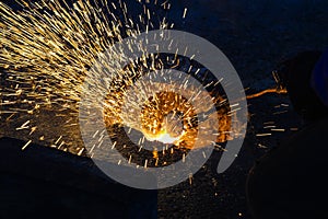 A gas cutter in production, a welder removes unnecessary metal residues with a gas cutter, sparks fly in different directions