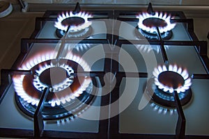 Gas kitchen stove with burning blue flame in dark