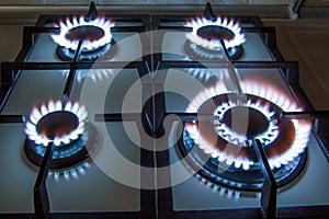 Gas kitchen stove with burning blue flame in dark