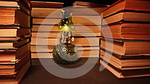 Gas lamp near stack of old books, slider footage in antique shop, bookstore.