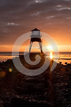Gas lighthouse by sea with sunrise sunset behind