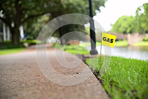 Gas line stake flag buried underground utility beside a footpath and river