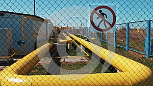 Gas main pipeline at a station for cleaning and storing oil and natural gas. Warning sign, unauthorized entry prohibited