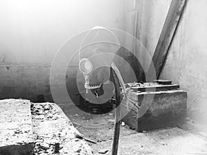 Gas mask hanging on a vertical stick in an abandoned building.