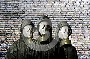 Gas masks. Three people with gas masks and brick wall behind with copy space