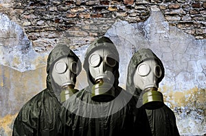 Gas masks. Three people with gas masks and brick wall behind with copy space