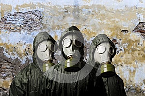 Gas masks. Three people with gas masks and brick wall behind with copy space