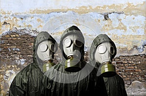 Gas masks. Three people with gas masks and brick wall behind with copy space