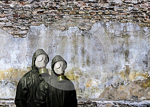 Gas masks. Two people with gas masks and brick wall behind with copy space