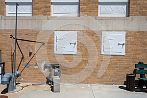 A gas meter and white metal utility doors in the side of a brick building