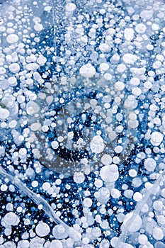 Gas methane bubbles frozen in winter ice of lake Baikal, abstract background