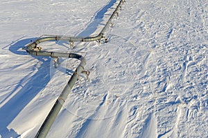 Gas pipelines, crane and pipes for gas and oil transportation, top view of an oil and gas pipe in white snow