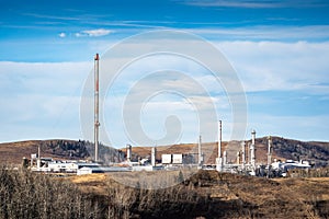 Gas plant with flare stack and industrial equipment overlooking the foothills near Cochrane Alberta Canada