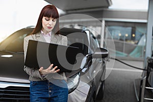 Gas station, business and people concept. Young pretty business woman on petrol station, while filling her car