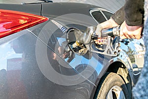 Gas station. Pump fuel petrol in tank car. Gasoline oil in nozzle. Close-up of the hand and the fuel gun. Blurred