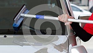 Gas station worker cleaning the car windshield with window squeegee